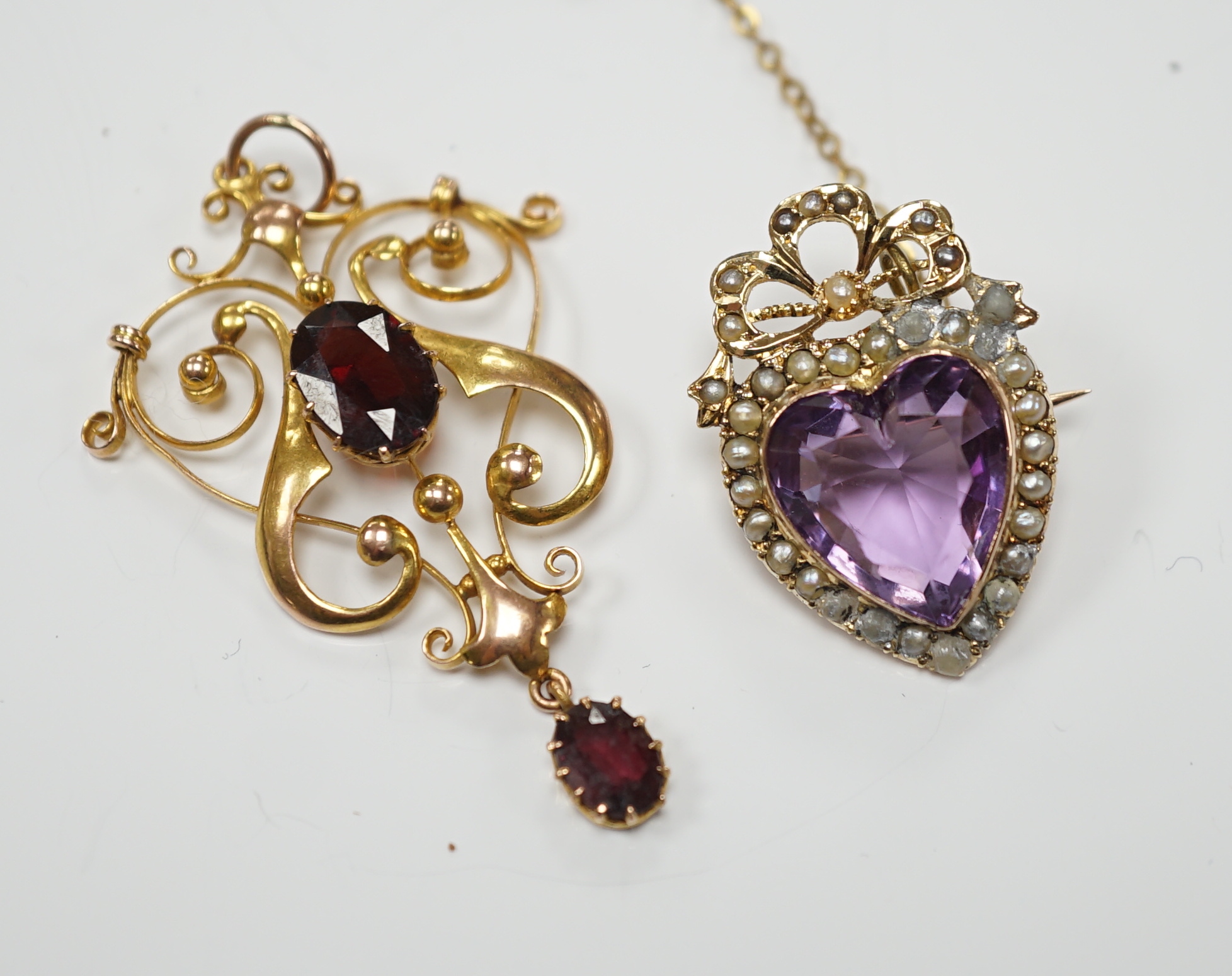 An early 20th century yellow metal, amethyst and seed pearl cluster set heart shaped brooch, 27mm, together with a similar yellow metal and two stone garnet set drop pendant, gross weight 9.3 grams.